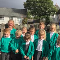 Click here for Class 1 A picture of four children cutting and sticking coloured shapes onto paper