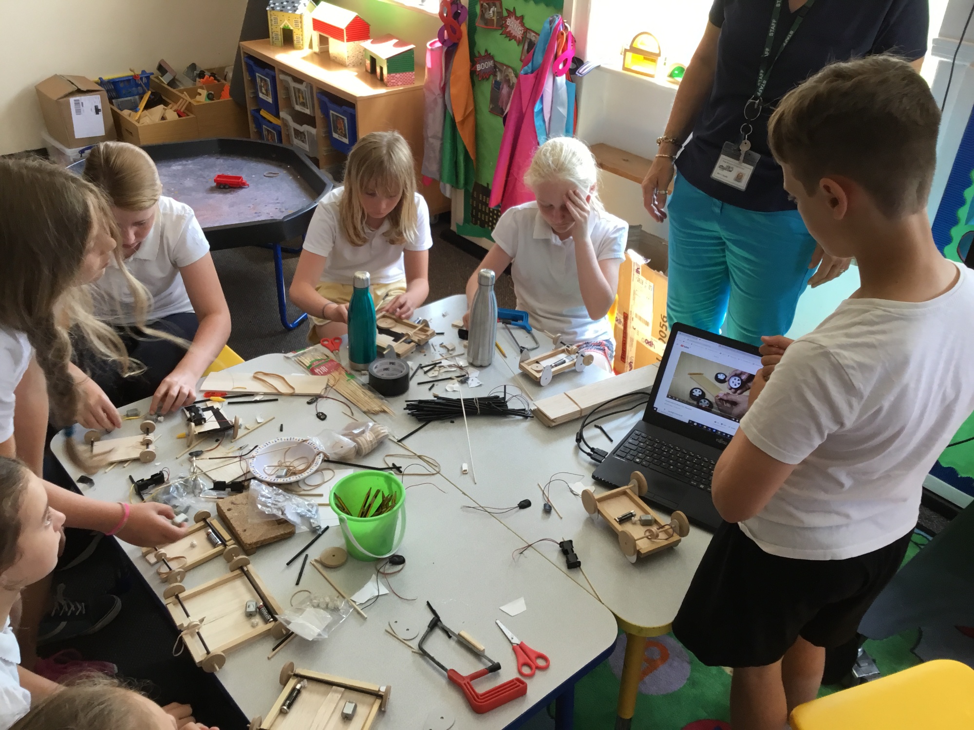 Children making moving vehicles from motors and balsa wood